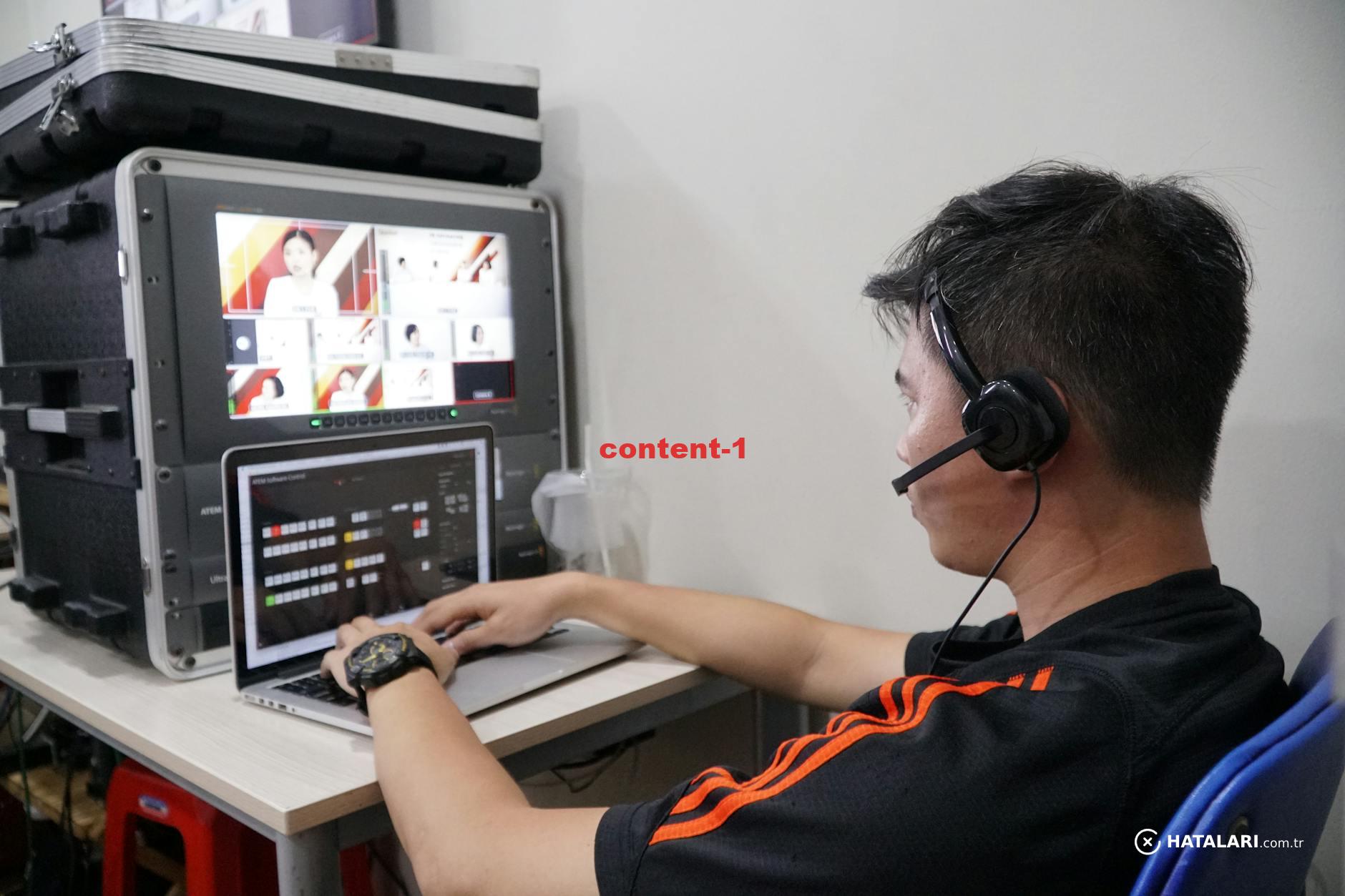 Technician manages multiple video feeds using laptop and monitor in studio setting.