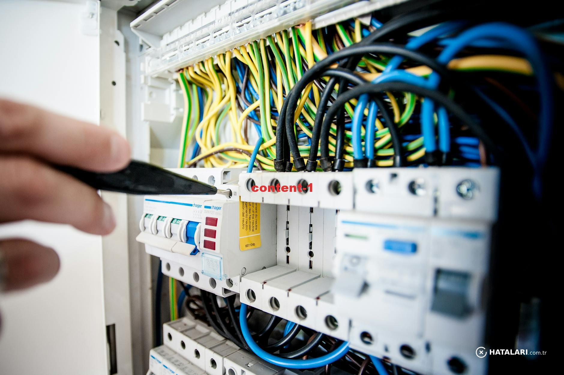 Hand of electrician working on a circuit breaker panel with colorful wires, ensuring safe electrical connections.